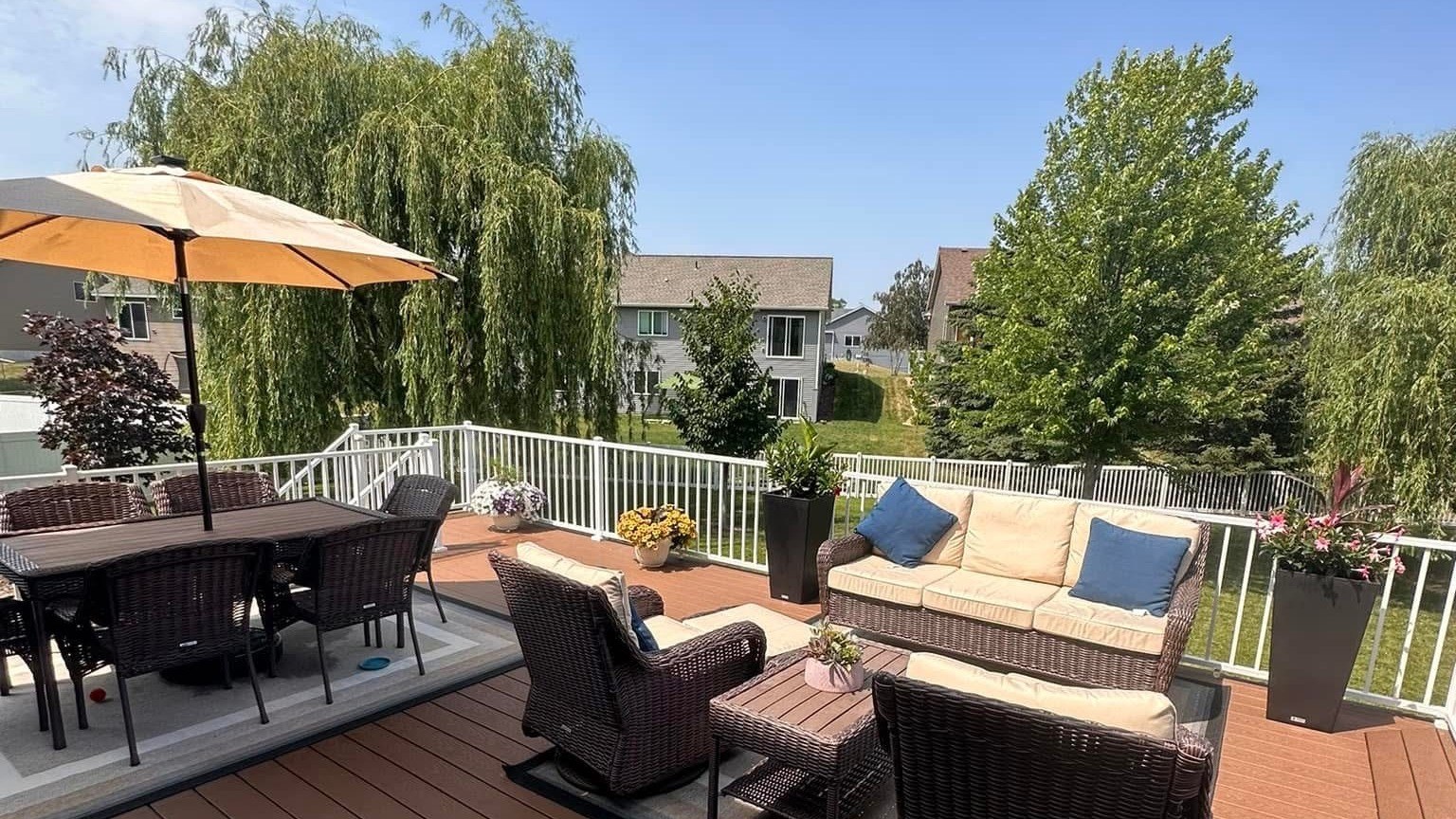 Finished composite deck with white railing, patio dining set and outdoor seating, a deck planned alongside siding and windows by a Lakeville exterior contractor.